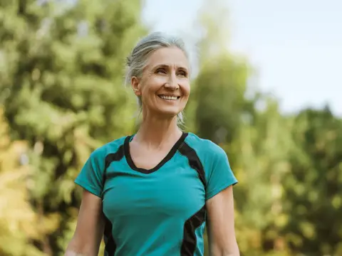 smiling senior woman exercising outdoors in a park.