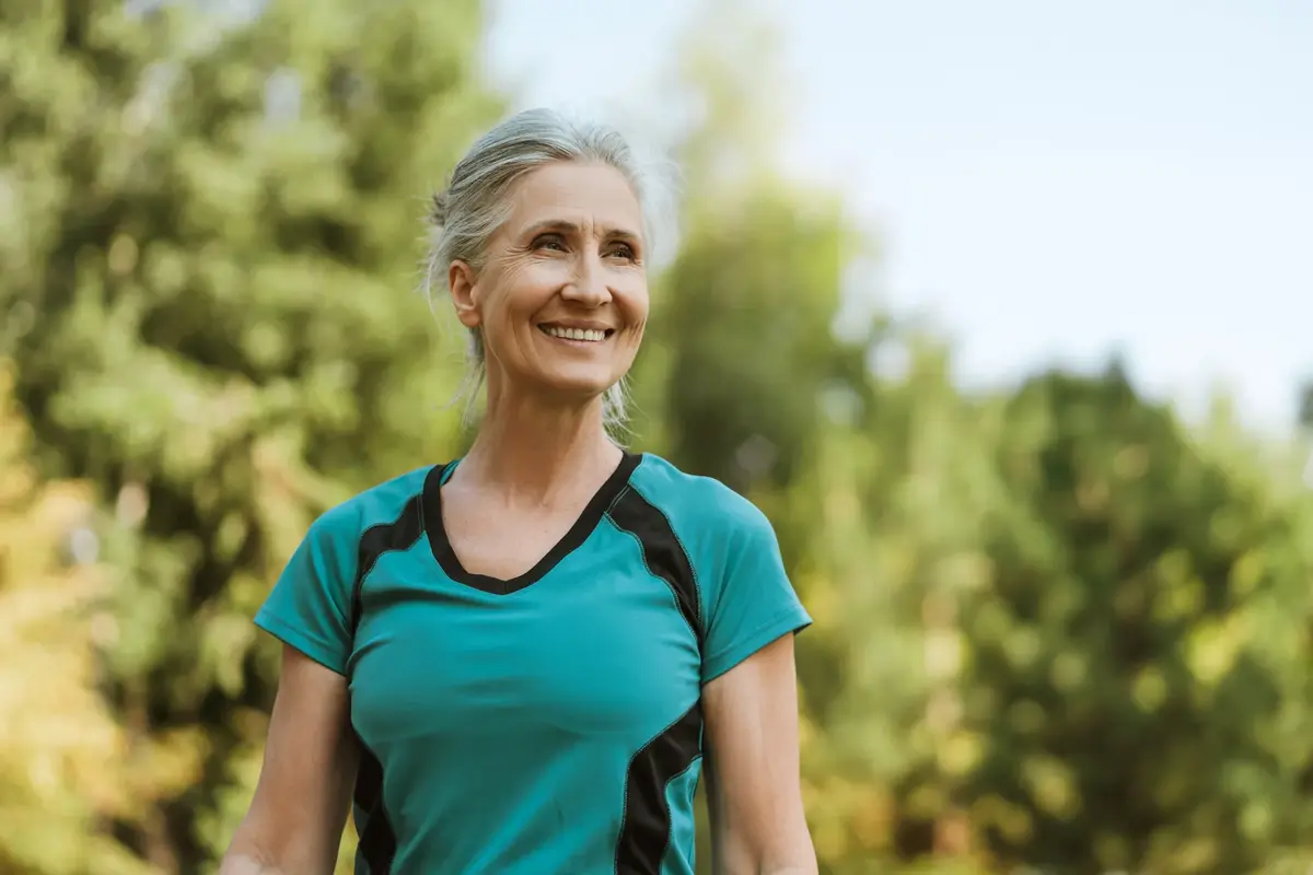 smiling senior woman exercising outdoors in a park.