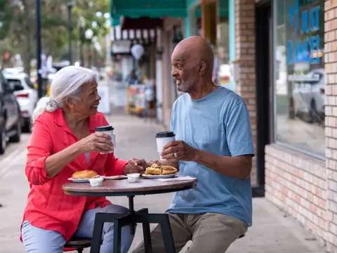 Elderly couple enjoying coffee and conversation at an outdoor cafe.