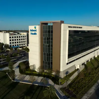 Aerial view of AdventHealth building with surrounding landscape and vehicles on the road.