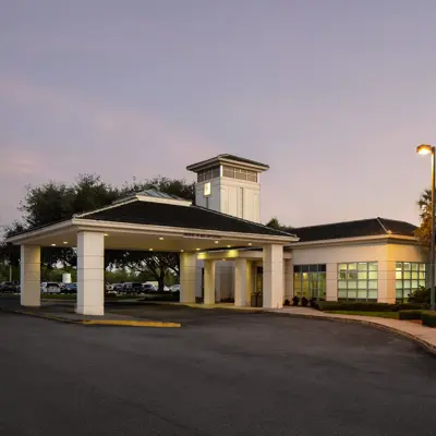 AdventHealth facility entrance with a covered walkway, palm trees, and a well-lit parking area.