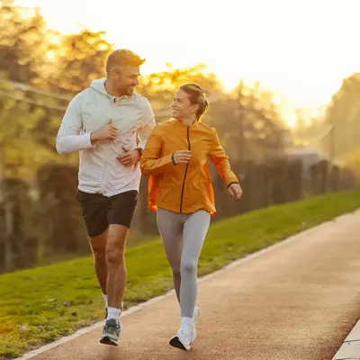 A couple running together outdoors at sunset.