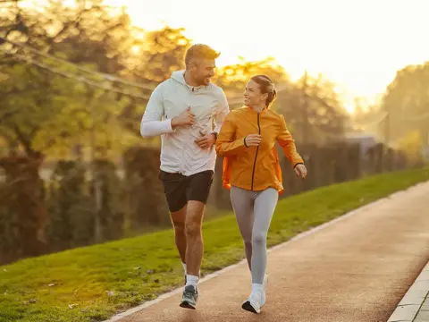 A couple running together outdoors at sunset.