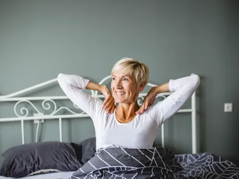 Senior woman wake up and she is stretching in bed