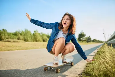 Ecstatic woman riding longboard on road in the countryside.