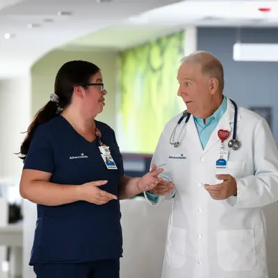 A nurse and doctor in an AdventHealth facility having a conversation.
