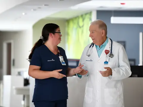 A nurse and doctor in an AdventHealth facility having a conversation.