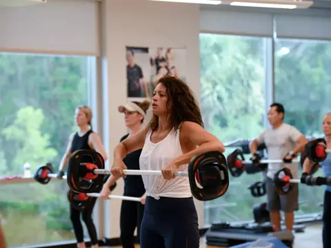 Group of people in a gym lifting weights together, promoting teamwork and fitness.