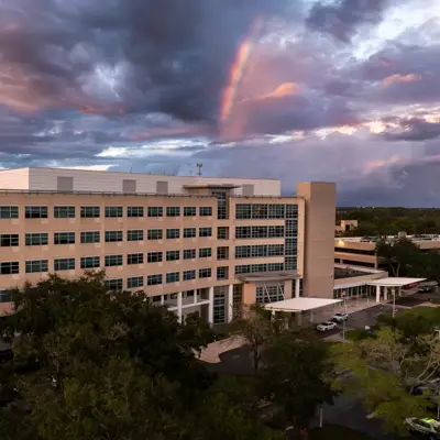 Aerial view of AdventHealth hospital with a rainbow in the sky and cloudy weather.