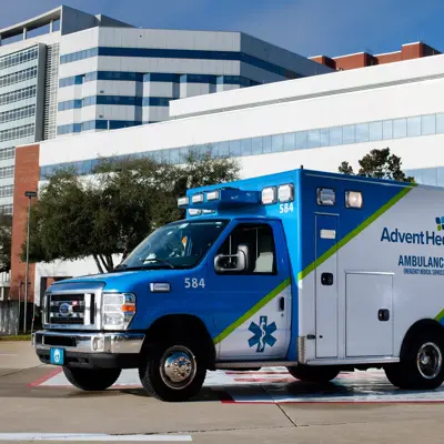 Blue AdventHealth ambulance parked in front of a modern hospital building.