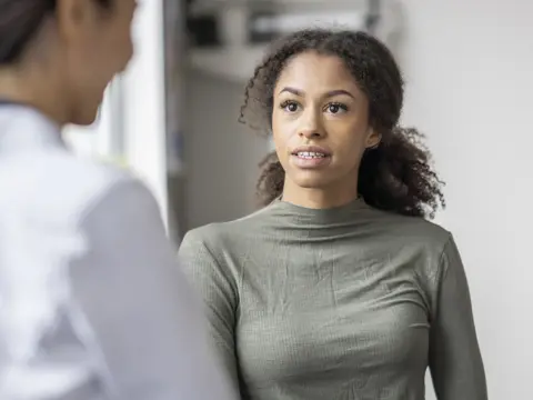 Women is speaking to their physician in a medical office.
