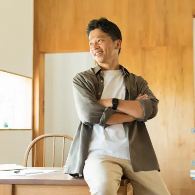 Man leaning on desk with arms crossed.