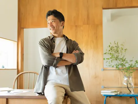 Man leaning on desk with arms crossed.