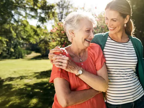 A young woman going for a walk with her elderly mother in the garden