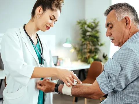 A man receives a bandage on his arm from a doctor.