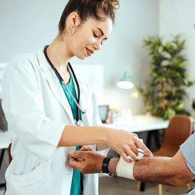 A man receives a bandage on his arm from a doctor.