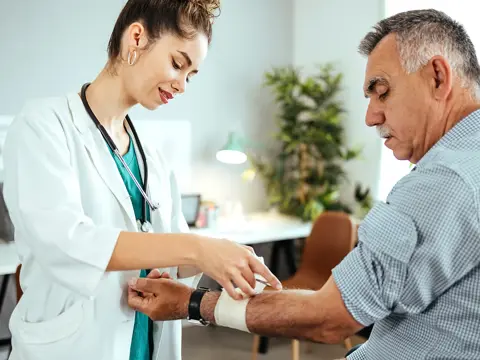 A man receives a bandage on his arm from a doctor.