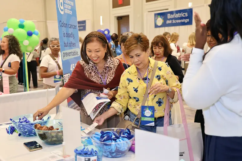 Two women reviewing educational materials at a colorectal cancer awareness booth during the AdventHealth Women's Health and Cancer Prevention Event