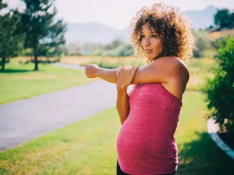 A pregnant woman stretching.
