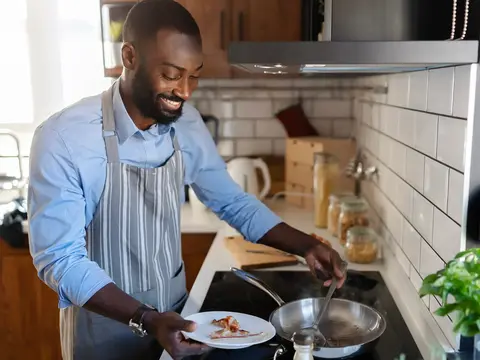 Man wearing an apron and cooking in his kitchen