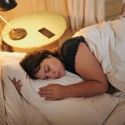 Woman, sleeping and home for peaceful weekend, tired and exhausted person in comfortable bedroom.
