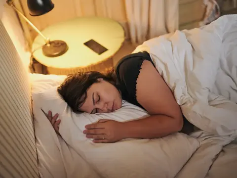 Woman, sleeping and home for peaceful weekend, tired and exhausted person in comfortable bedroom.