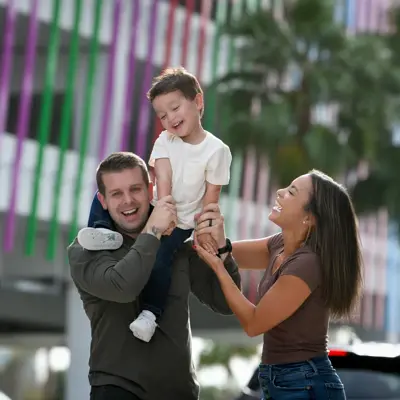 A happy family of three, consisting of a man, a woman, and a child, are smiling and posing for a photo.