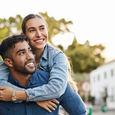 Woman hugging a man from behind while on a walk surrounded by trees