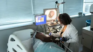 Health care professional performing an endoscopic procedure on a patient lying in a hospital bed in a modern clinical room with medical monitors