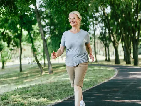 Smiling active senior woman jogging running and walking doing fitness in the park.
