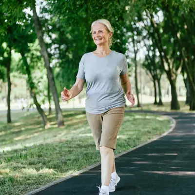 Smiling active senior woman jogging running and walking doing fitness in the park.