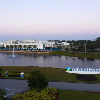 Aerial view of AdventHealth facility with a large pond and fountain in front.