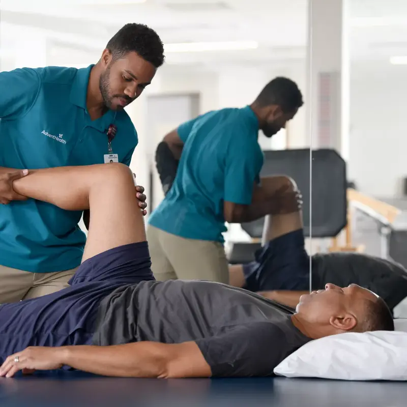 Physical therapist assisting a patient with leg exercises in a rehabilitation clinic.