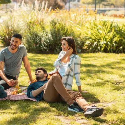 A group of young adults sitting on the ground at a park.