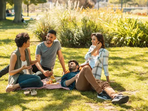 A group of young adults sitting on the ground at a park.