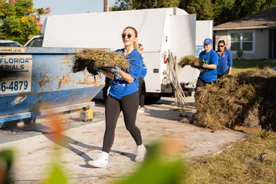 A woman helping carry and install sod at charity event.