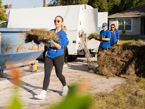 A woman helping carry and install sod at charity event.