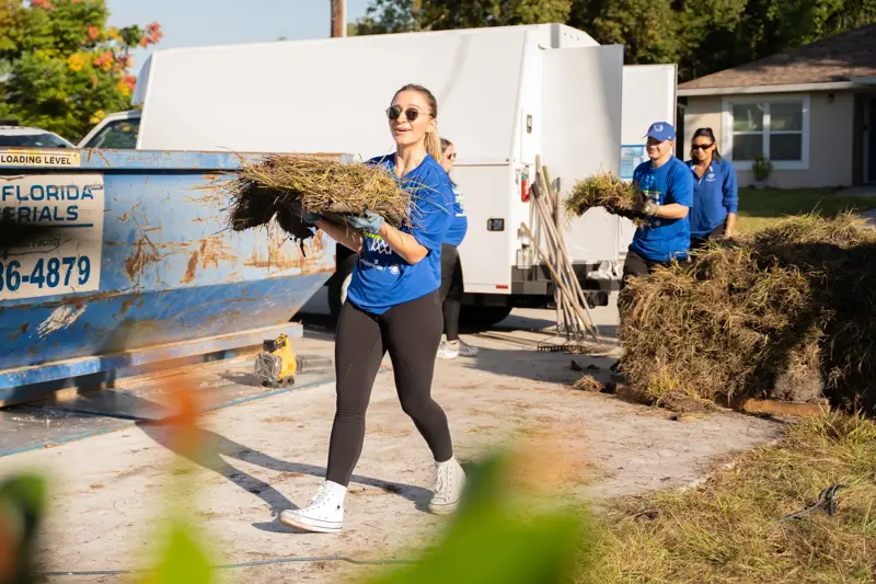 A woman helping carry and install sod at charity event.