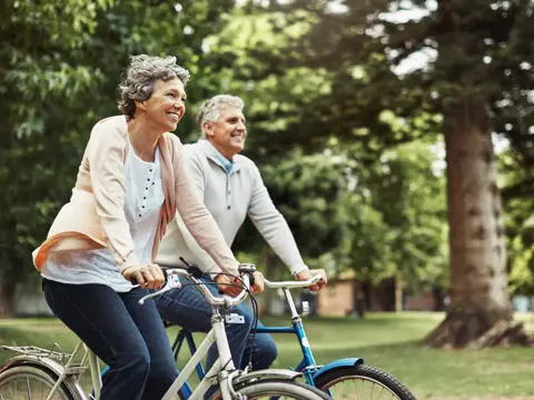 Senior couple riding bicycles in a park, smiling and enjoying the outdoors.