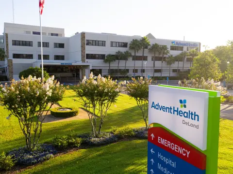 AdventHealth DeLand hospital exterior with sign directing to emergency, hospital and medical.