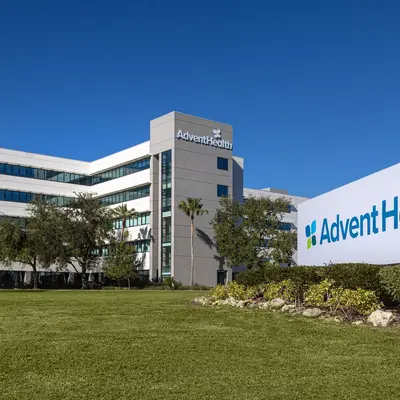AdventHealth building with a large sign in front on a sunny day with blue sky.