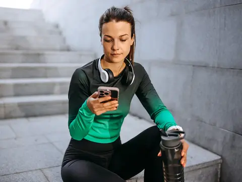 A young female runner takes a break and checks her phone.