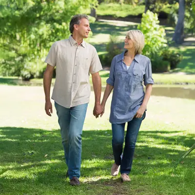 A middle-aged couple walking in their yard. 