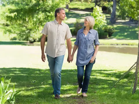 A middle-aged couple walking in their yard. 
