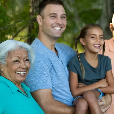 A smiling family of four stands together in a park, showcasing unity and joy.