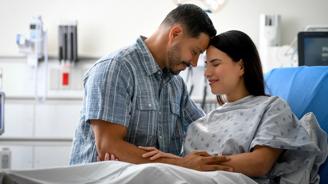 A man and woman in a hospital room, smiling and holding hands.
