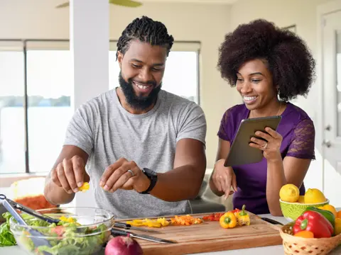 A couple preparing a healthy meal together in a bright kitchen, smiling and engaged.