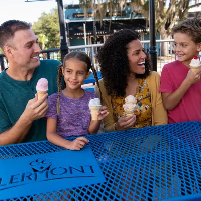 Family of four enjoying ice cream cones at a table with a Clermont sign.