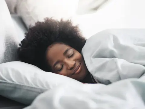 A young woman sleeping in her bed in the morning at home.