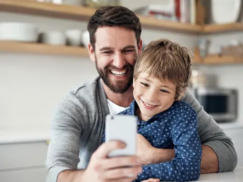 A man and his young son looking at a cell phone.